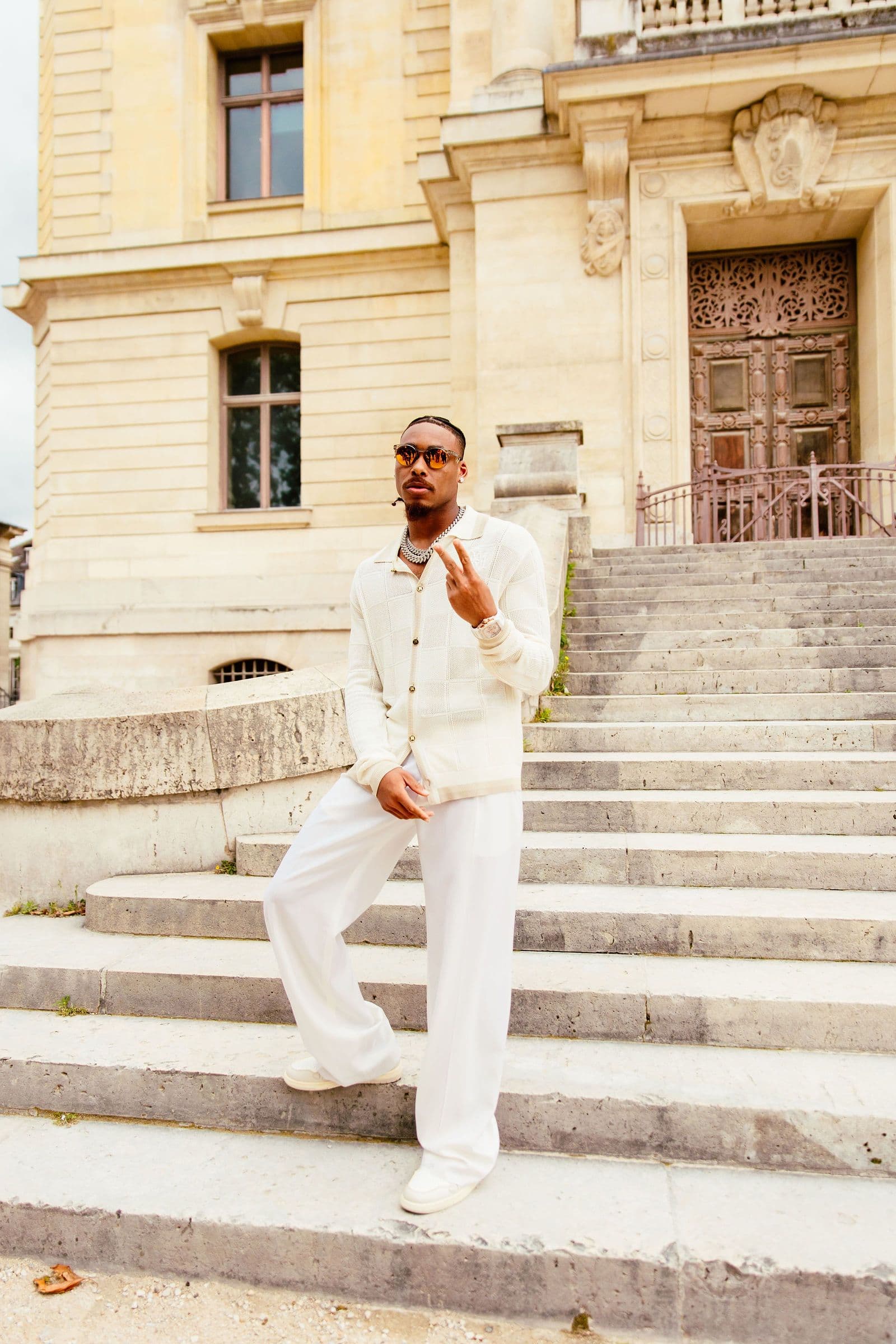 Justin Jefferson stands on stone steps in front of a large building, making a peace sign