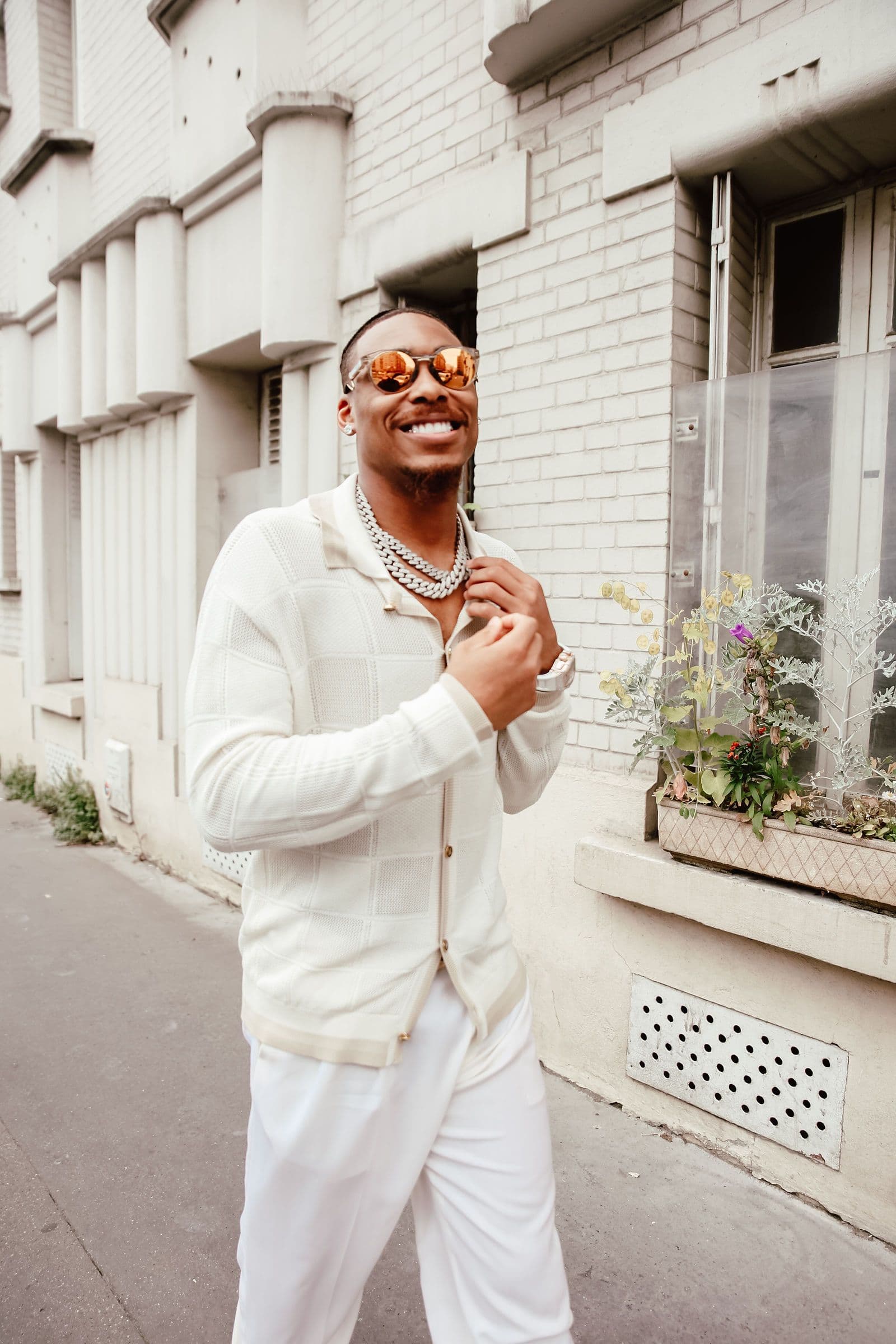 Justin Jefferson smiles wearing sunglasses and a white outfit on a street
