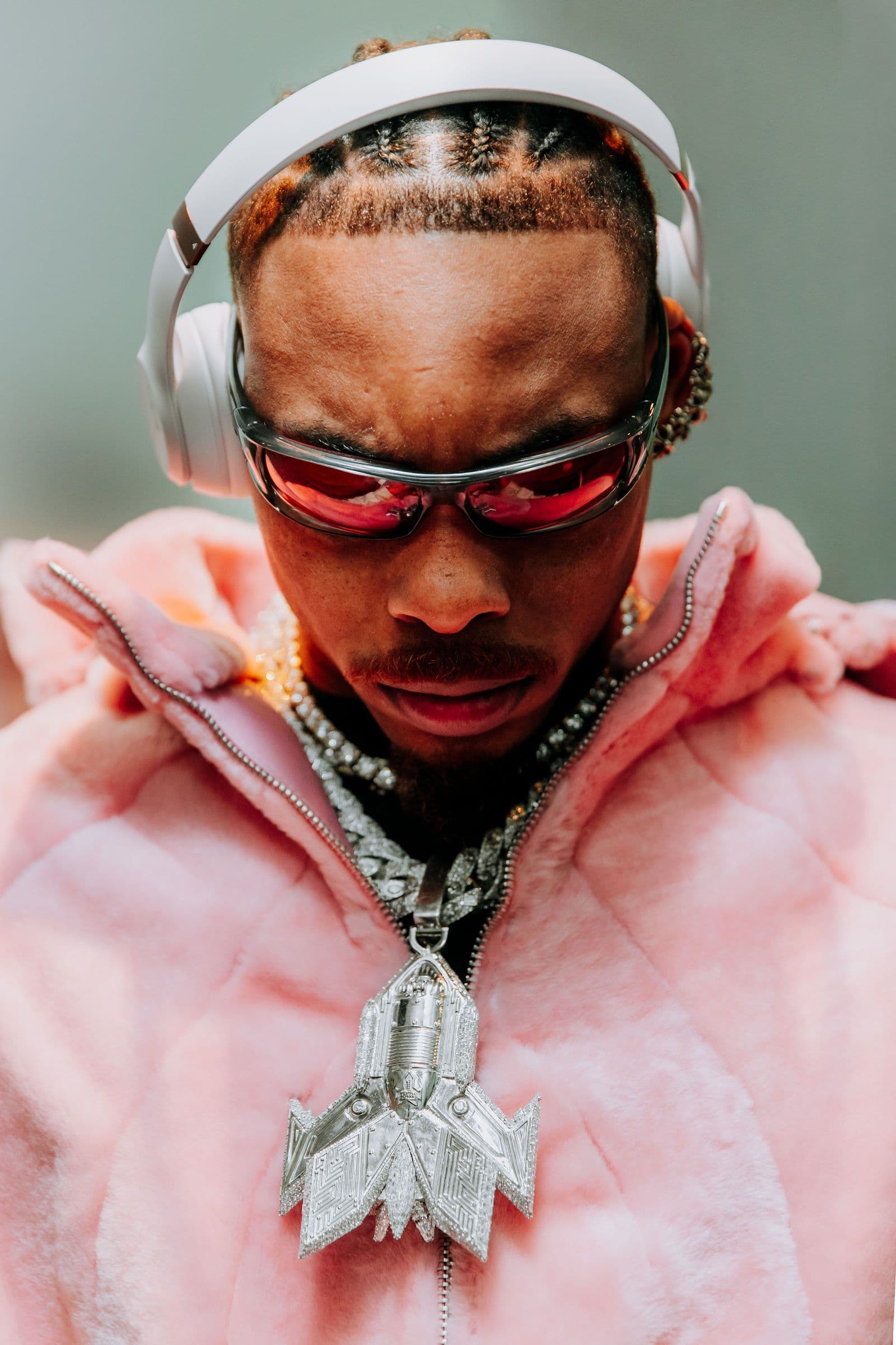 Justin Jefferson wears white headphones, red sunglasses, a pink jacket, and a large pendant