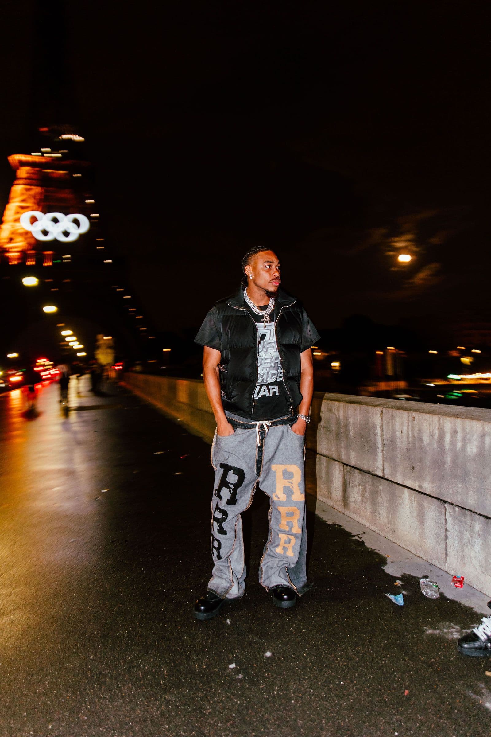 Justin Jefferson stands on a bridge at night with the Eiffel Tower in the background