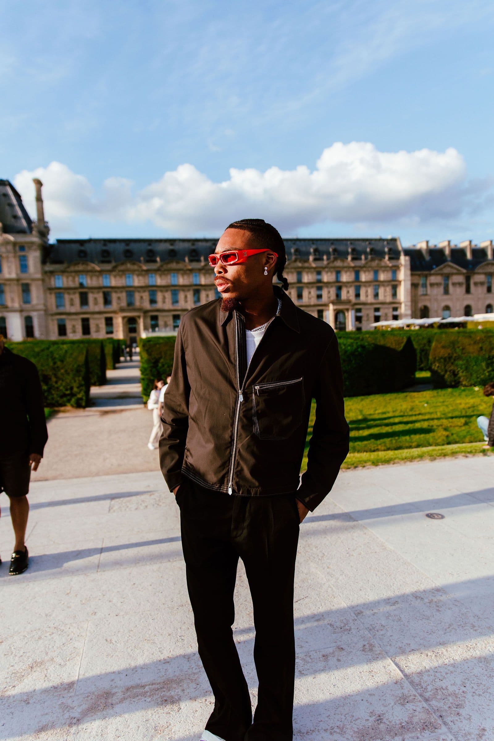 Justin Jefferson stands outdoors in black attire and red sunglasses, looking right