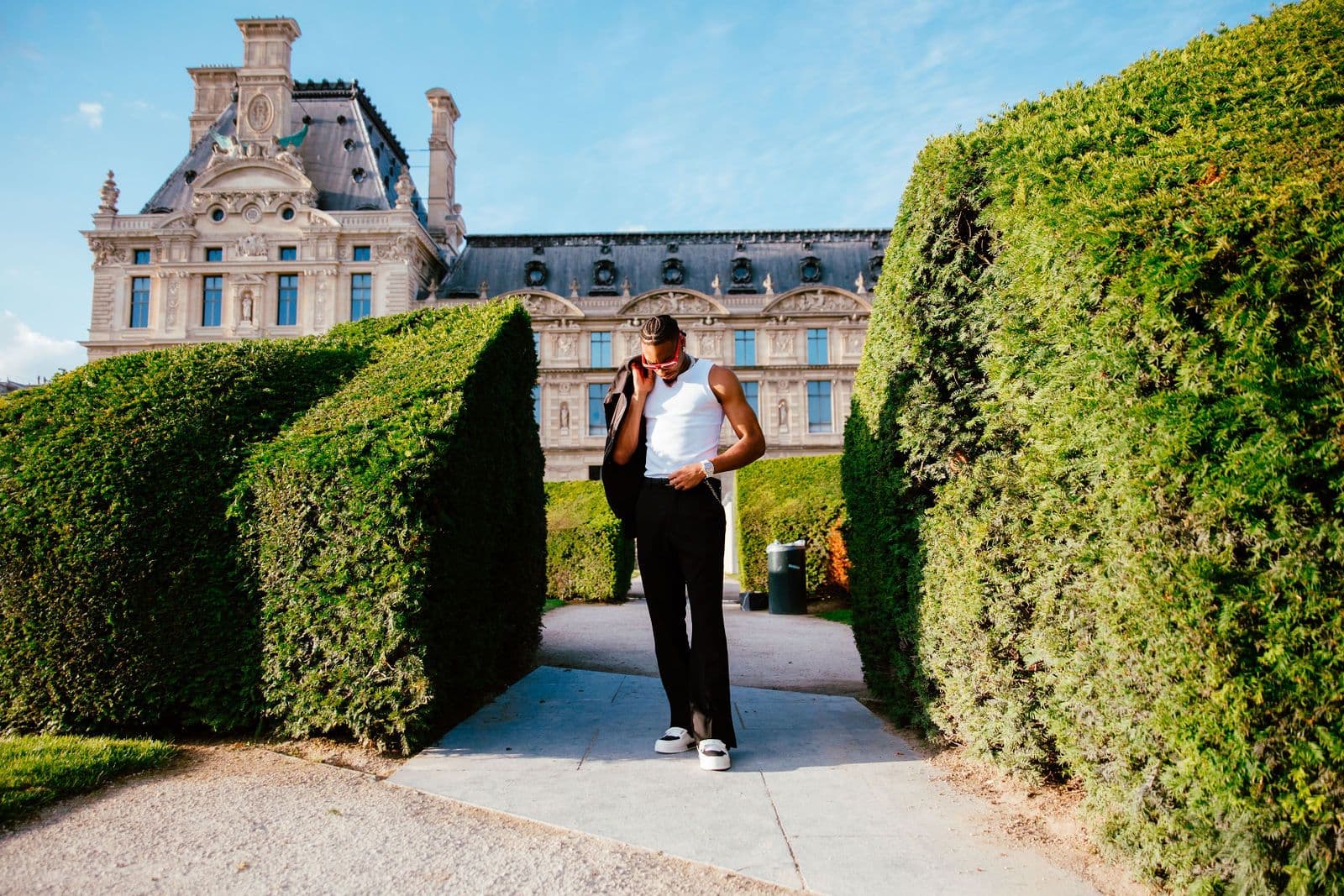 Justin Jefferson stands between hedges with a historic building in the background, wearing a white tank top