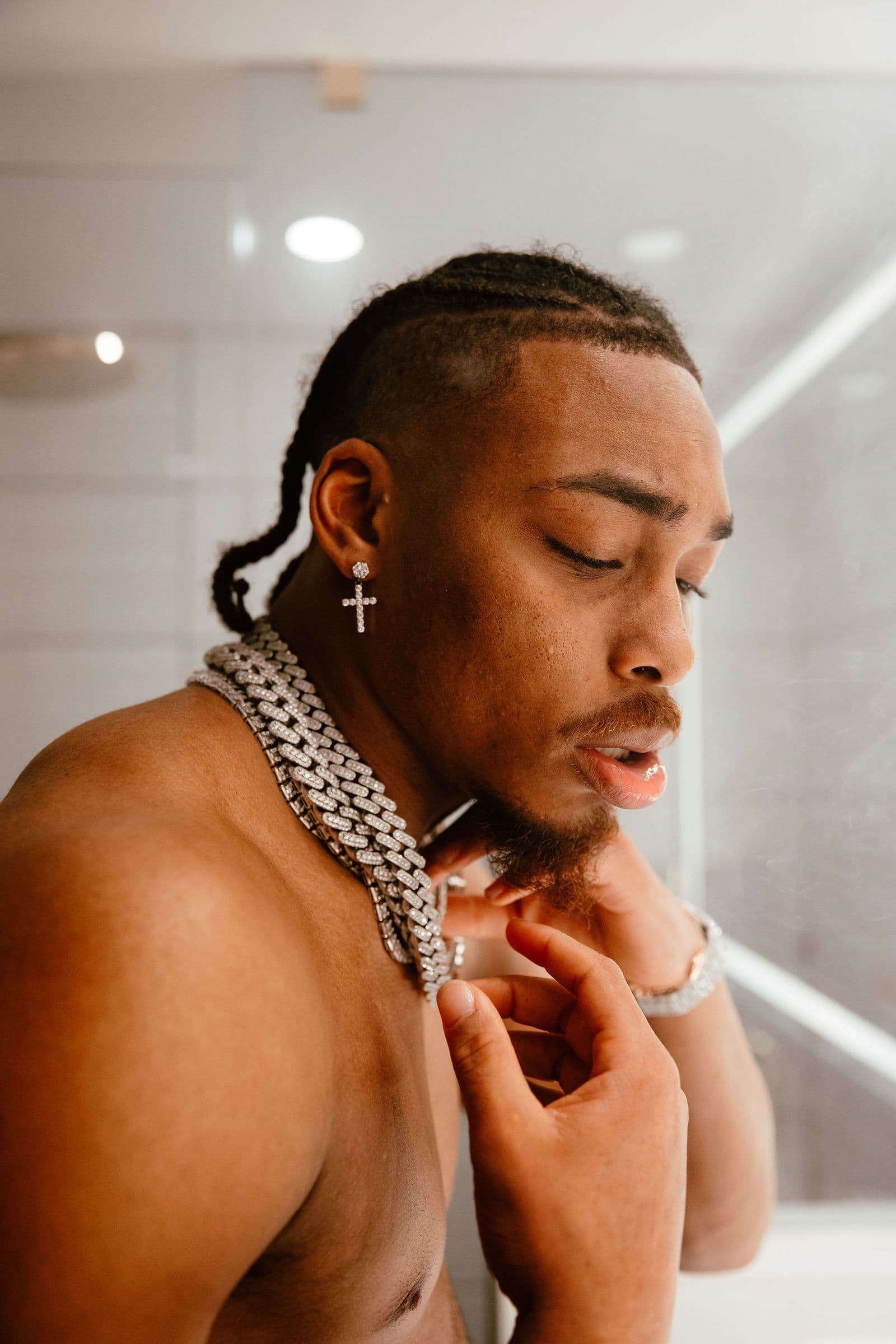 Justin Jefferson adjusts a diamond chain around his neck, looking down