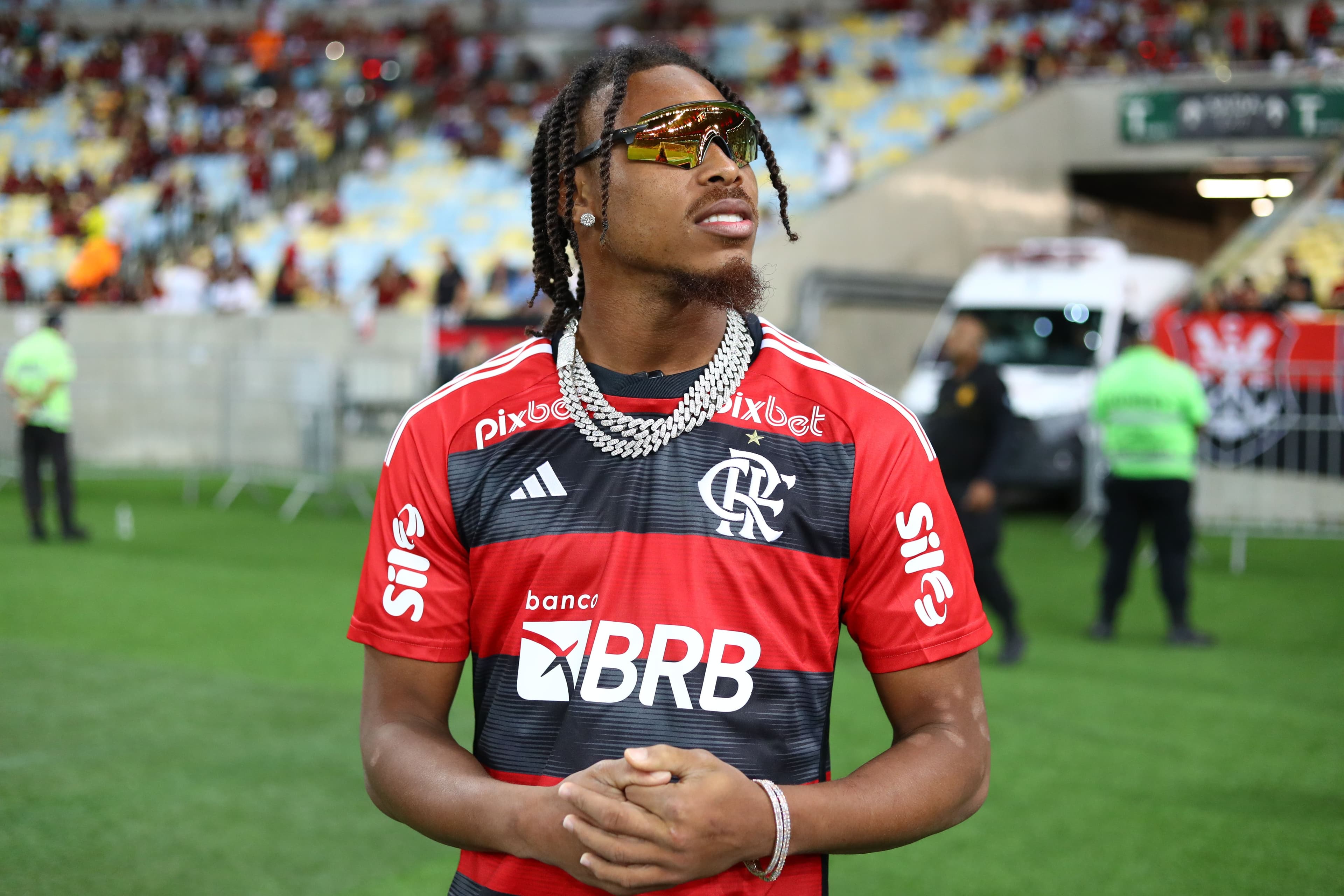 Justin Jefferson stands on a field wearing a red and black jersey and sunglasses