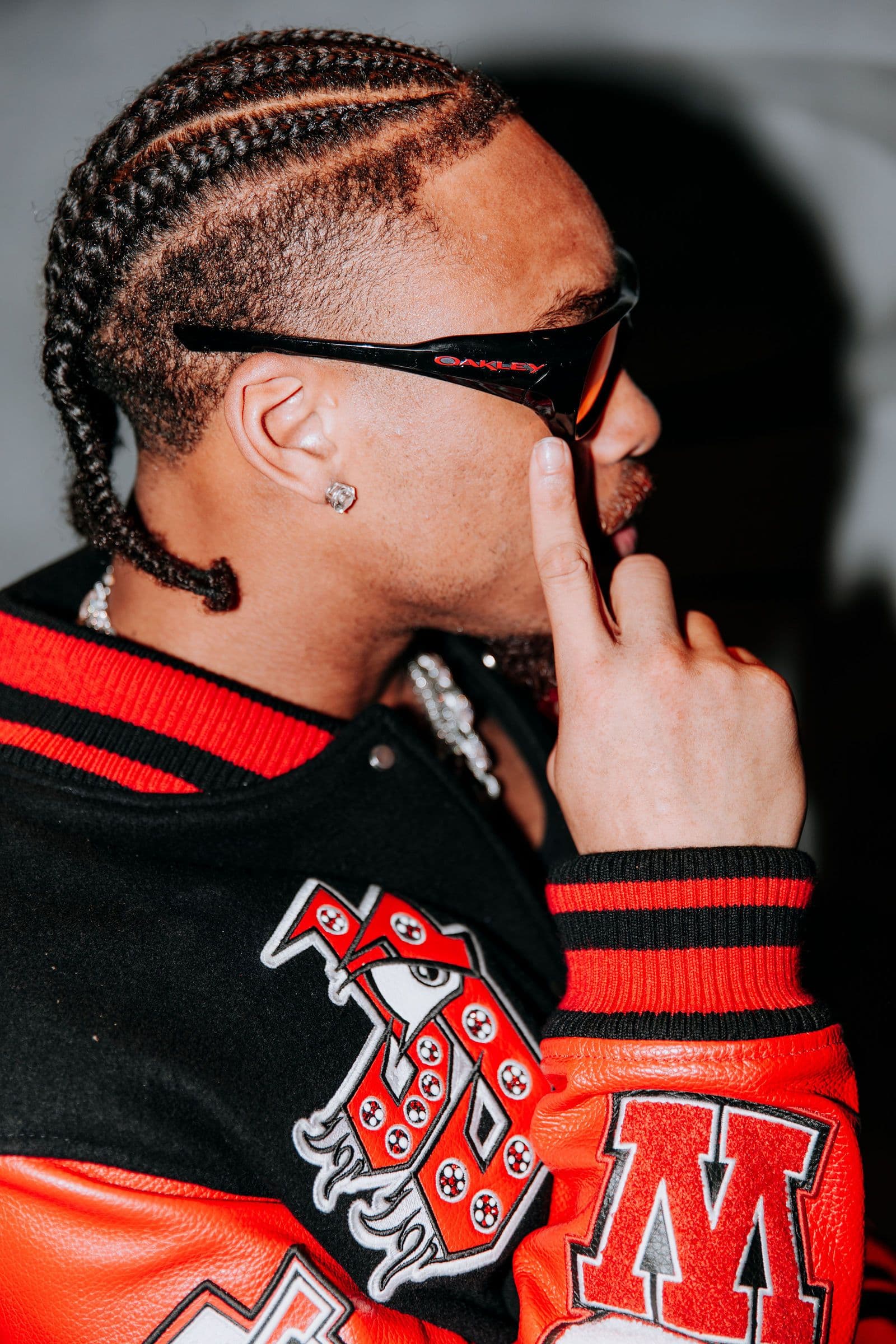 Justin Jefferson wears sunglasses and a letterman jacket, touching his face, viewed from the side