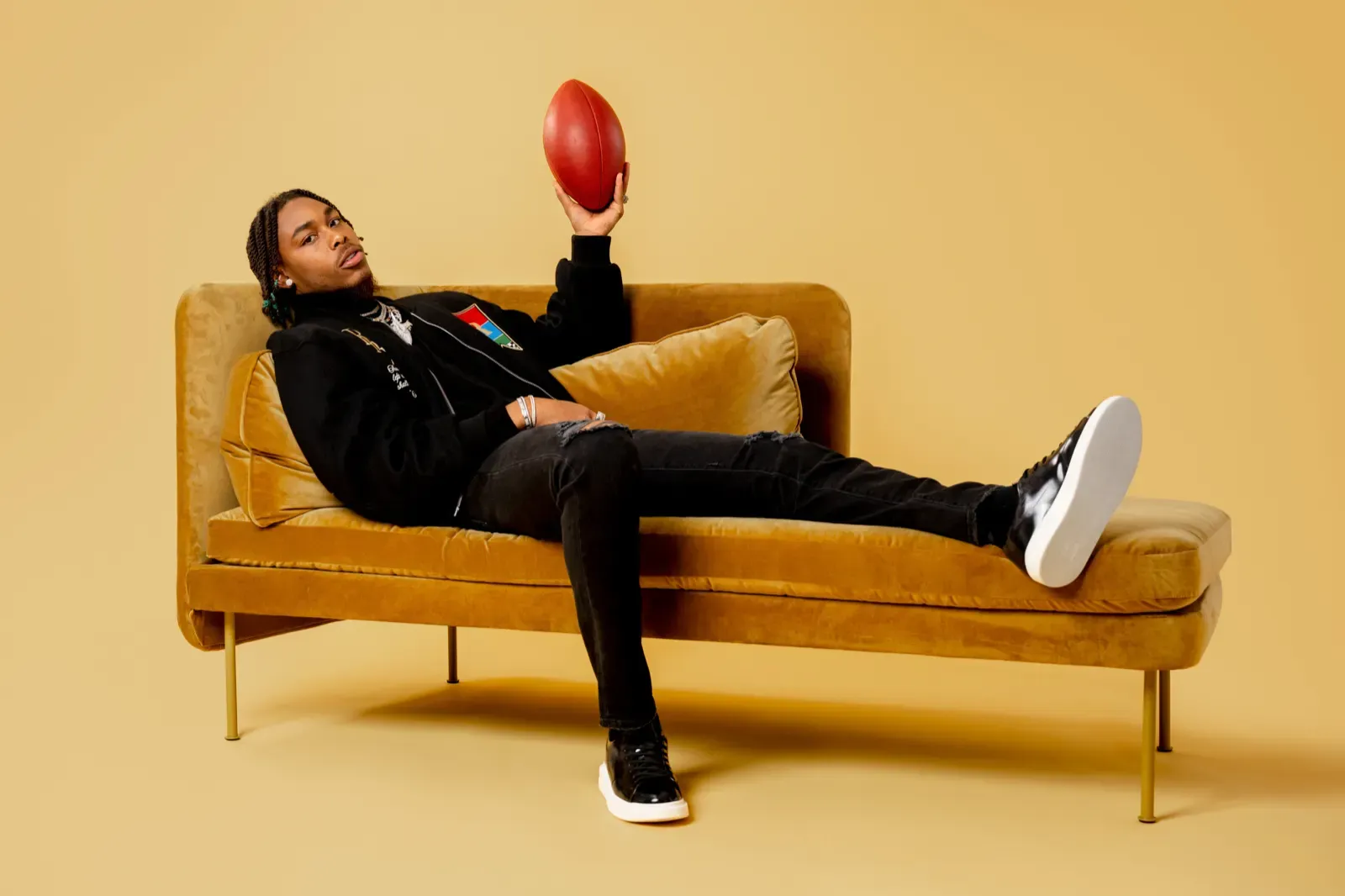 Justin Jefferson lounging across a mustard couch in an editorial set
