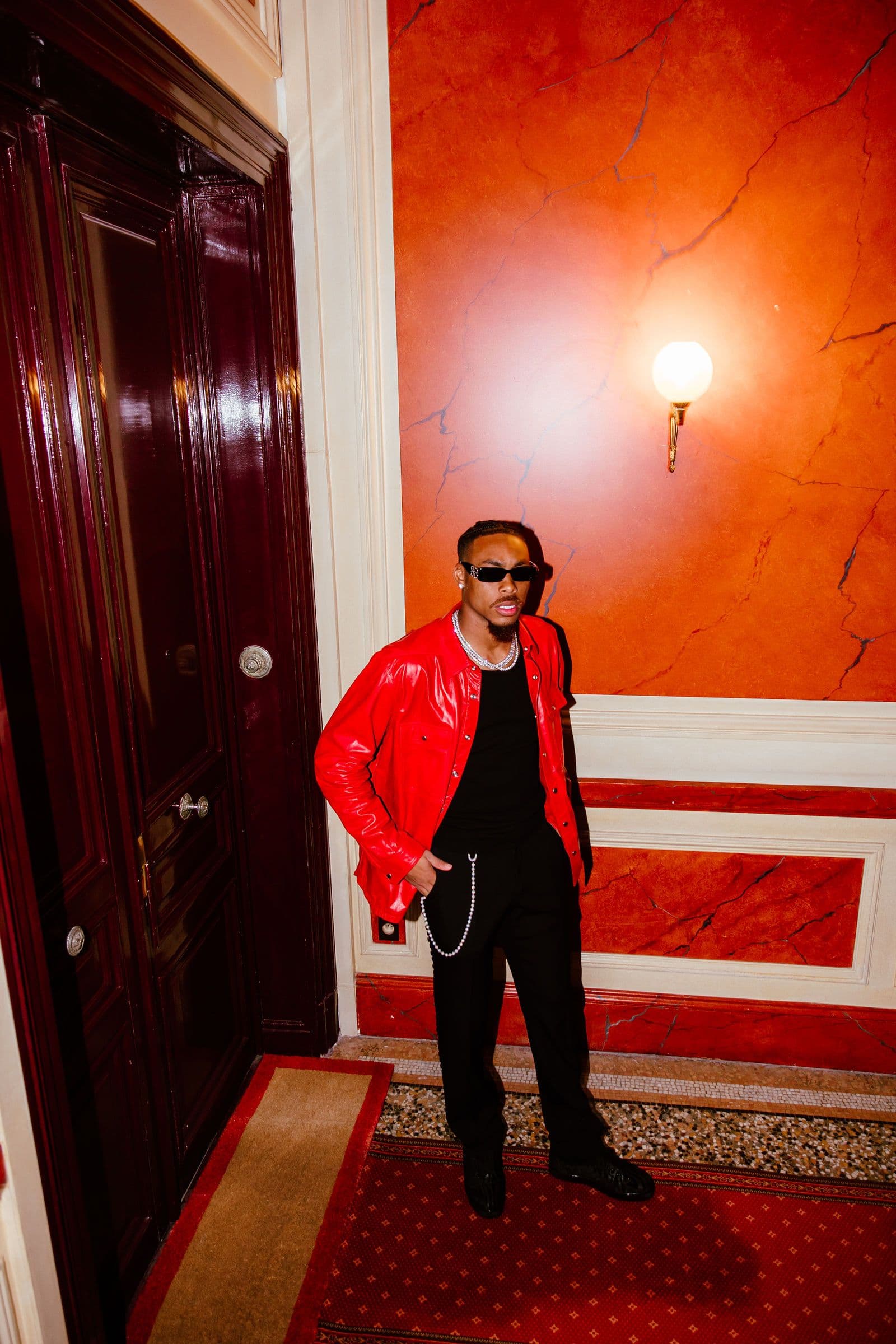 Justin Jefferson stands in a hallway wearing a red jacket and sunglasses