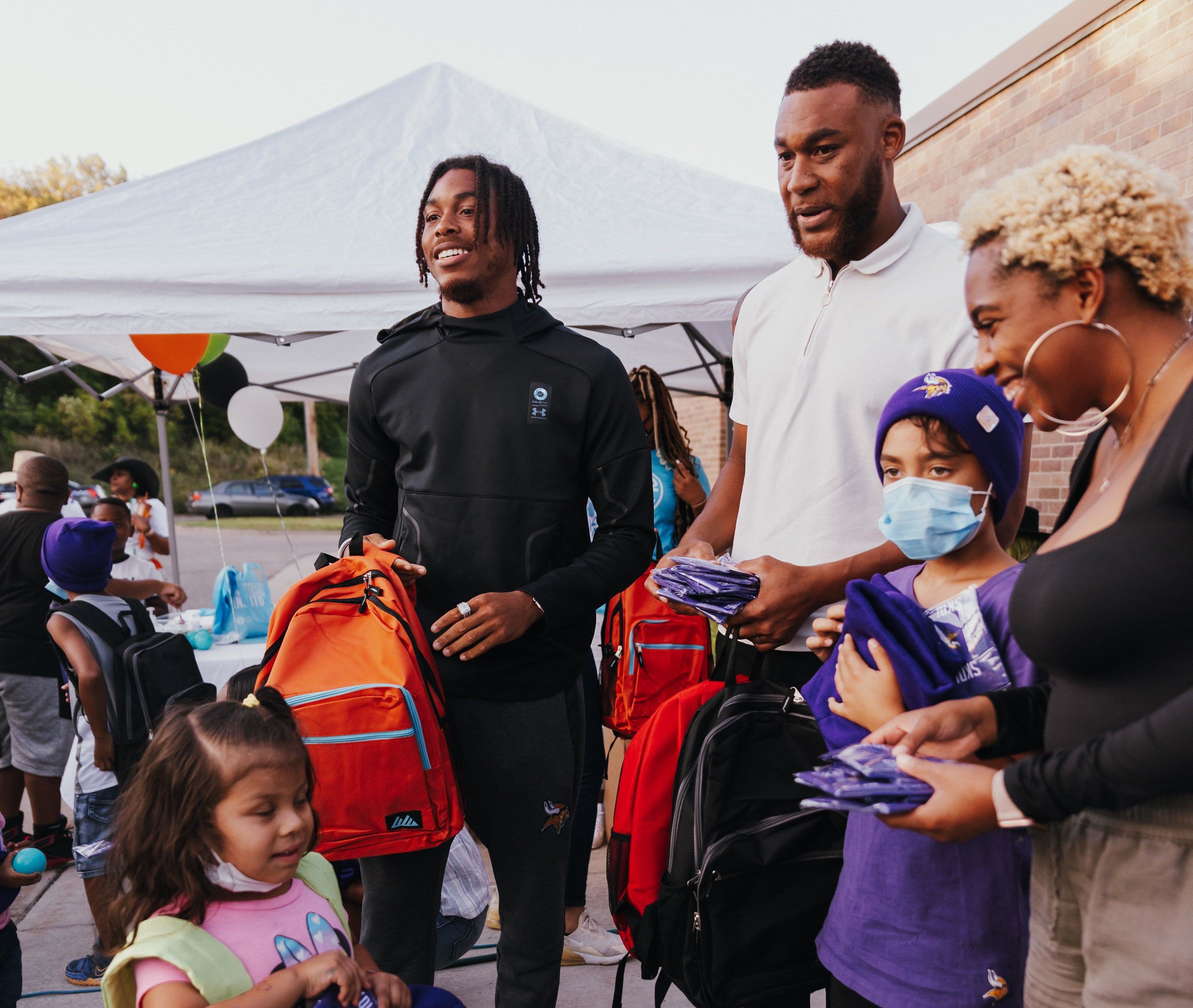 Handing out backpacks under the tent at the Backpack Drive